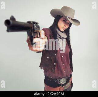 Ich bin der Sheriff um diese Teile.... Ganzkörperaufnahme einer attraktiven jungen Frau in Cowboy-Kleidung. Stockfoto