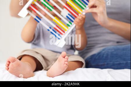 Zählen lernen. Eine Mutter und ihr Kleinkind zählen auf einen Abakus. Stockfoto