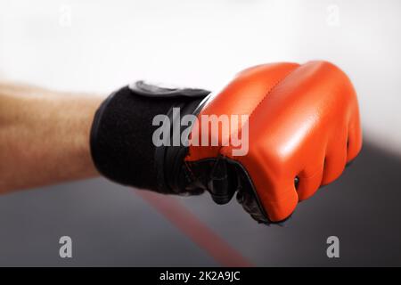 Gib alles, was du hast. Kurzer Schuss einer Kampfsportfäuste in einem roten Kickboxen-Handschuh. Stockfoto