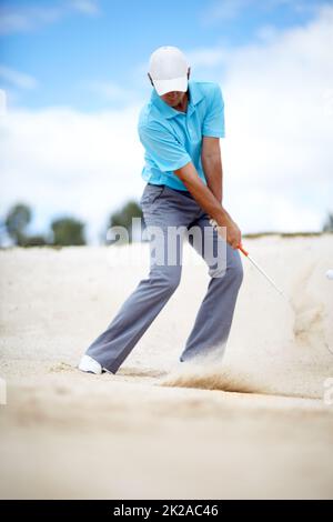 Im Bunker. Ein Bild eines jungen Golfspielers, der seinen Ball bei einem Golfspiel aus einem Bunker hacken kann. Stockfoto