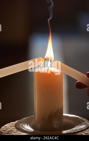 Ihre ewige Flamme entzünden. Kurze Nahaufnahme eines Paares, das während der Hochzeitszeremonie Kerzen anzündet. Stockfoto