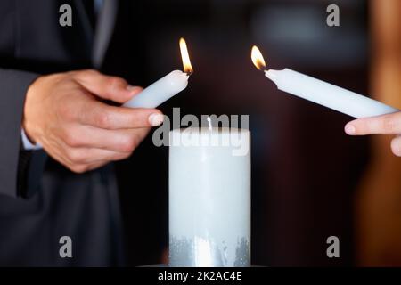 Die Flamme ihrer Liebe. Nahaufnahme eines Paares, das während der Hochzeitszeremonie Kerzen anzündet. Stockfoto