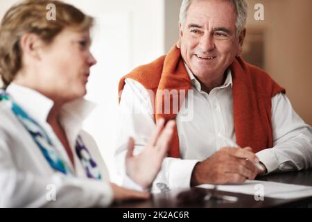 Unterhaltung an der Rezeption. Ein älterer Mann und seine Frau füllen an der Rezeption des Hotels Formulare aus. Stockfoto