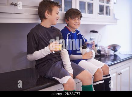 Jungen werden Jungen sein. Kurzer Schuss von zwei Jungen, die nach dem Fußballtraining kalte Getränke getrunken haben. Stockfoto