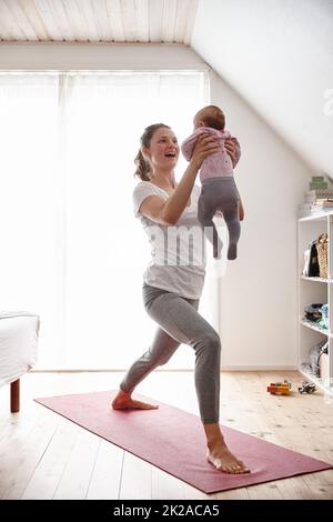 Körperbewusste Mutter und Baby. Aufnahme einer attraktiven jungen Frau, die sich beim Yoga mit ihrem kleinen Mädchen verklebt. Stockfoto