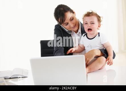 Es ist schwer, zwei Rollen auf einmal zu spielen. Berufstätigen Mutter am Telefon sprechen, während ein weinendes Baby halten. Stockfoto