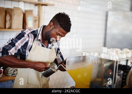 Kaffee Express. Ein kurzer Schuss eines hübschen Barista, der in einem Café eine Espressomaschine benutzt. Stockfoto