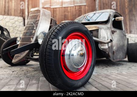 Nahaufnahme Detail Rad pov Blick vintage alte amerikanische Hot Rod in der Garage geparkt, Ausstellung von fest. Schöne Retro Rost gestylt Oldtimer Fahrzeug vorne Stockfoto