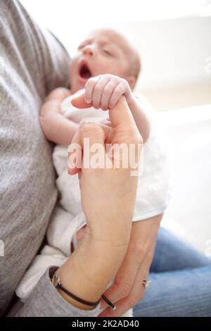 Einschlafen in den Armen ihrer Mutter. Aufnahme eines neugeborenen Mädchens, das von ihrer Mutter festgehalten wird. Stockfoto