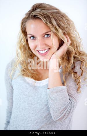 Ein hübsches, süßes Lächeln. Porträt einer hübschen jungen Blondine, die Sie süß anlächelt. Stockfoto