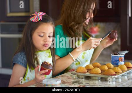 Shes ein großer kleiner Bäcker. Niedliches kleines Mädchen, das zu Hause mit ihrem Kindermädchen backt. Stockfoto