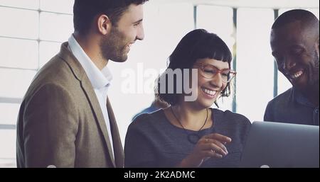 Sie beeindruckt immer. Eine kurze Aufnahme einer Gruppe junger Designer, die sich in ihrem Büro ein digitales Tablet angeschaut haben. Stockfoto