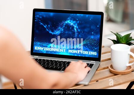 Konzeptionelle Beschriftung Umgebungsüberwachung. Geschäftsidee Grundlage der Produktion natürlicher Folgenabschätzungen Handtippen auf Laptop neben Coffe Becher und Plant Working From Home. Stockfoto