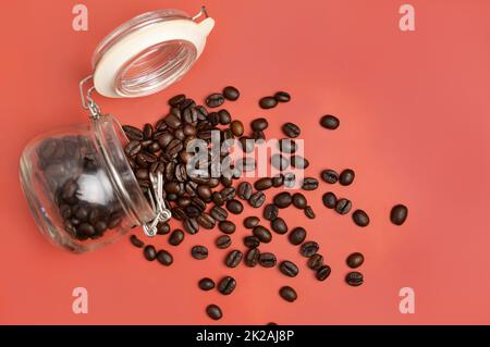 Geröstete Kaffeebohnen in einem Glasglas Draufsicht auf rosa Hintergrund mit Kopierraum. Repräsentieren Frühstück, Energie, Frische oder Aroma Stockfoto