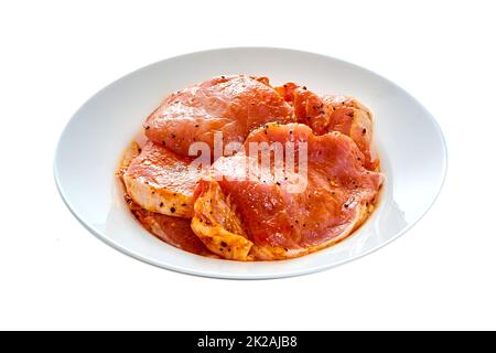 Schweinefleisch in Marinade liegt auf einem weißen Teller auf einem weißen isolierten Hintergrund Stockfoto