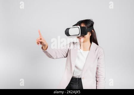 Lächelnde Frau, die ein VR-Headset trägt, das während des Virtual-Reality-Erlebnisses Luft berührt Stockfoto