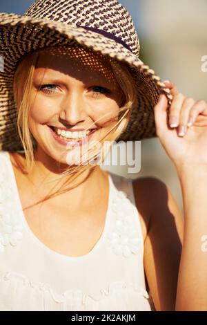 Genießen Sie einen Tag in der Sonne. Eine schöne junge Frau, die einen Strohhut trägt. Stockfoto