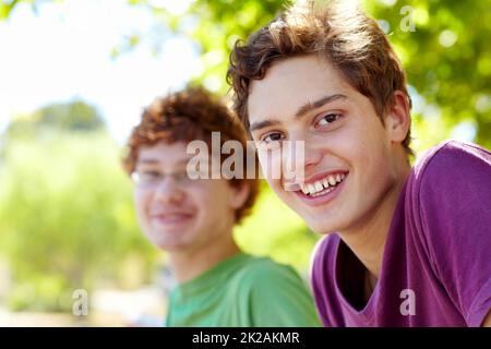 Mit meinem besten Freund rumhängen. Portrait von zwei Jungen, die an einem sonnigen Tag in einem Park sitzen. Stockfoto