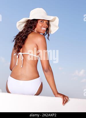 Sommerschönheit unter der afrikanischen Sonne. Rückansicht einer schönen afrikanischen Frau in einem Bikini, der sich in der Sommersonne sonnt. Stockfoto