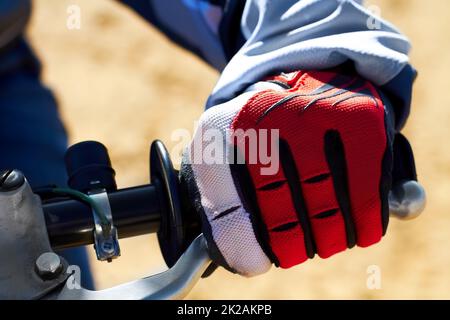 Beim Motocross ist der Schutz der Hände unerlässlich. Nahaufnahme eines Schmutzes Biker Hand trägt einen Handschuh. Stockfoto