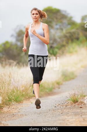 Laufen für Fitness. Eine junge Frau, die auf einer unbefestigten Straße läuft. Stockfoto