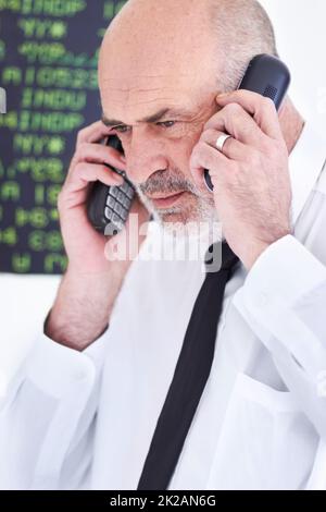 HES ist ein guter Finanzdienstleister. Aufnahme eines reifen Börsenmaklers, der auf zwei Mobiltelefonen gleichzeitig spricht. Stockfoto