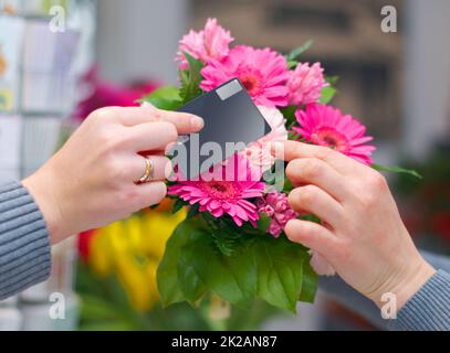 Beweisen, dass Schönheit gekauft werden kann. Kurzer Schuss einer Frau, die Blumen mit ihrer Kreditkarte von einem Floristen kauft. Stockfoto