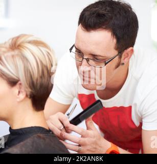 Hes ein solcher Perfektionist. Ein Friseur, der den letzten Schliff auf seinen clientamp039s-er Kopf legte. Stockfoto