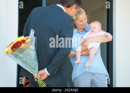 Die Romantik am Leben erhalten. Kurzer Schuss eines Mannes, der seine Frau mit Blumen überraschte. Stockfoto