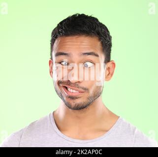 Ah, duh. Ausgeschnittene Aufnahme eines hübschen jungen Mannes, der im Studio ein Gesicht vor grünem Hintergrund macht. Stockfoto