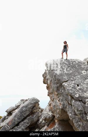 Die Welt hinter sich lassen. Ein Felskletterer, der auf einer Klippe steht. Stockfoto