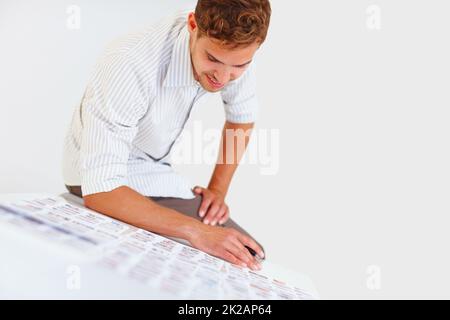 Männlicher Fotograf sitzt auf dem Tisch. Männlicher Fotograf, der auf dem Tisch sitzt und seine Fotos ansieht. Stockfoto