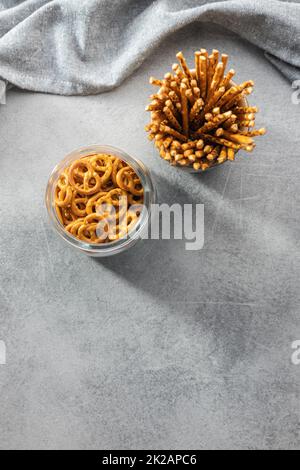 Mini-Brezeln und gesalzene Stäbchen. Knuspriger, gesalzener Snack auf dem Küchentisch. Stockfoto