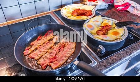 Spiegeleier machen Spiegeleier Schinkenwürste in der Pfanne. Stockfoto