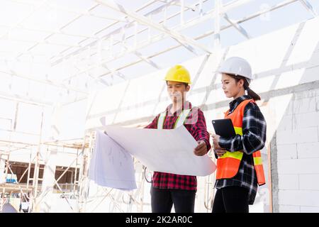 Architekt und Bauherr besprechen den Plan mit dem Bauplan des Gebäudes auf der Baustelle Stockfoto