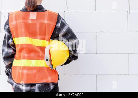 Rückansicht des Technikers, Architekten, Vorgesetzten tragen reflektierende Kleidung zur Sicherheit der Arbeit Halten Sie den Schutzhelm Stockfoto