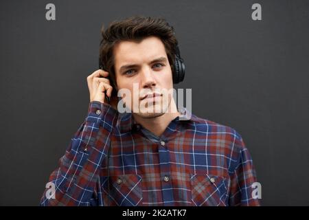 Haben Sie etwas gesagt? Ein junger Mann, der draußen steht und Musik hört? Stockfoto