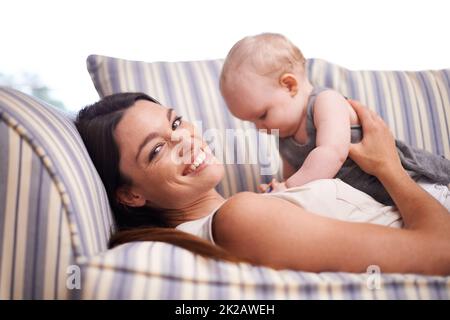 HES mein Stolz und meine Freude. Porträt einer attraktiven jungen Frau und ihres kleinen Mädchens, das auf dem Sofa liegt. Stockfoto