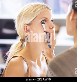 Für einen Make-up-Künstler ist jedes Gesicht eine Leinwand. Hübsche junge Frau, die ihr Make-up von einem Stylist aufgetragen hat. Stockfoto