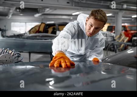 Mechaniker in Uniform Schleifen lackierte Karosserie Stockfoto