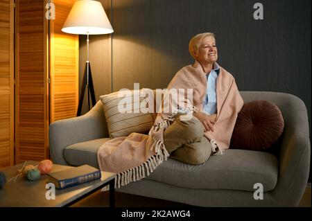 Zufriedene alte Frau in Decke eingehüllt entspannend Stockfoto