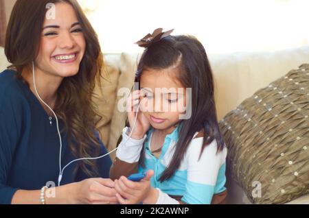 Die Liebe zur Musik teilen. Nettes kleines Mädchen, das mit ihrer Mutter Musik hört. Stockfoto