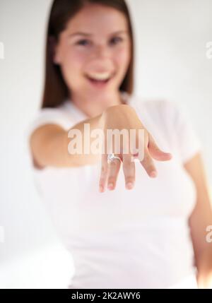 Diamanten sind ihre beste Freundin. Porträt einer schönen jungen Frau, die lächelt und ihre Hand hochhält, um ihren Verlobungsring zu zeigen. Stockfoto