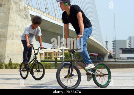 Abwechselnd ihre Sachen zu zeigen. BMX-Fahrer machen Tricks in der Stadt. Stockfoto