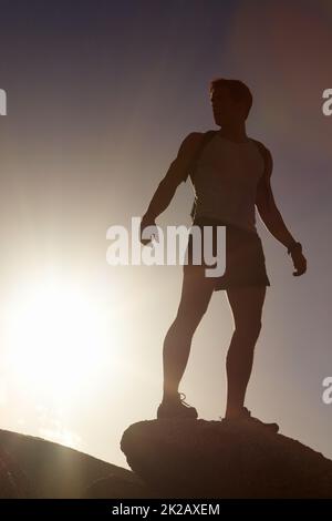 Ein Leben voller Abenteuer. Eine Silhouette eines Mannes, der auf einer Klippe steht. Stockfoto