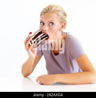 Ich hoffe, niemand sieht mich betrügen - Diäten. Junge Frau stopfte ihren Mund voll mit Schokoladenkuchen. Stockfoto