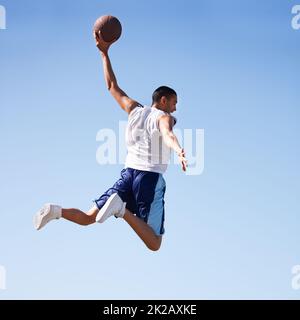 Der Schwerkraft trotzen. Ein junger Athlet, der einen fliegenden Sprung gemacht hat. Stockfoto