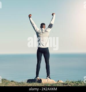 Ich habe es getan. Rückansicht eines nicht erkennbaren jungen Mannes, der mit erhobenen Händen im Freien beim Training stand. Stockfoto