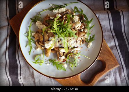 Warmer Pilzsalat mit Feta-Käse und Rucola auf einer Leinenserviette Stockfoto