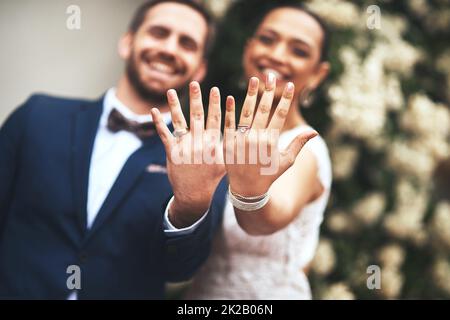 Unsere Symbole der Liebe aufblitzen lassen. Aufnahme eines glücklichen jungen Ehepaares, das am Hochzeitstag ihre Ringe zeigt. Stockfoto